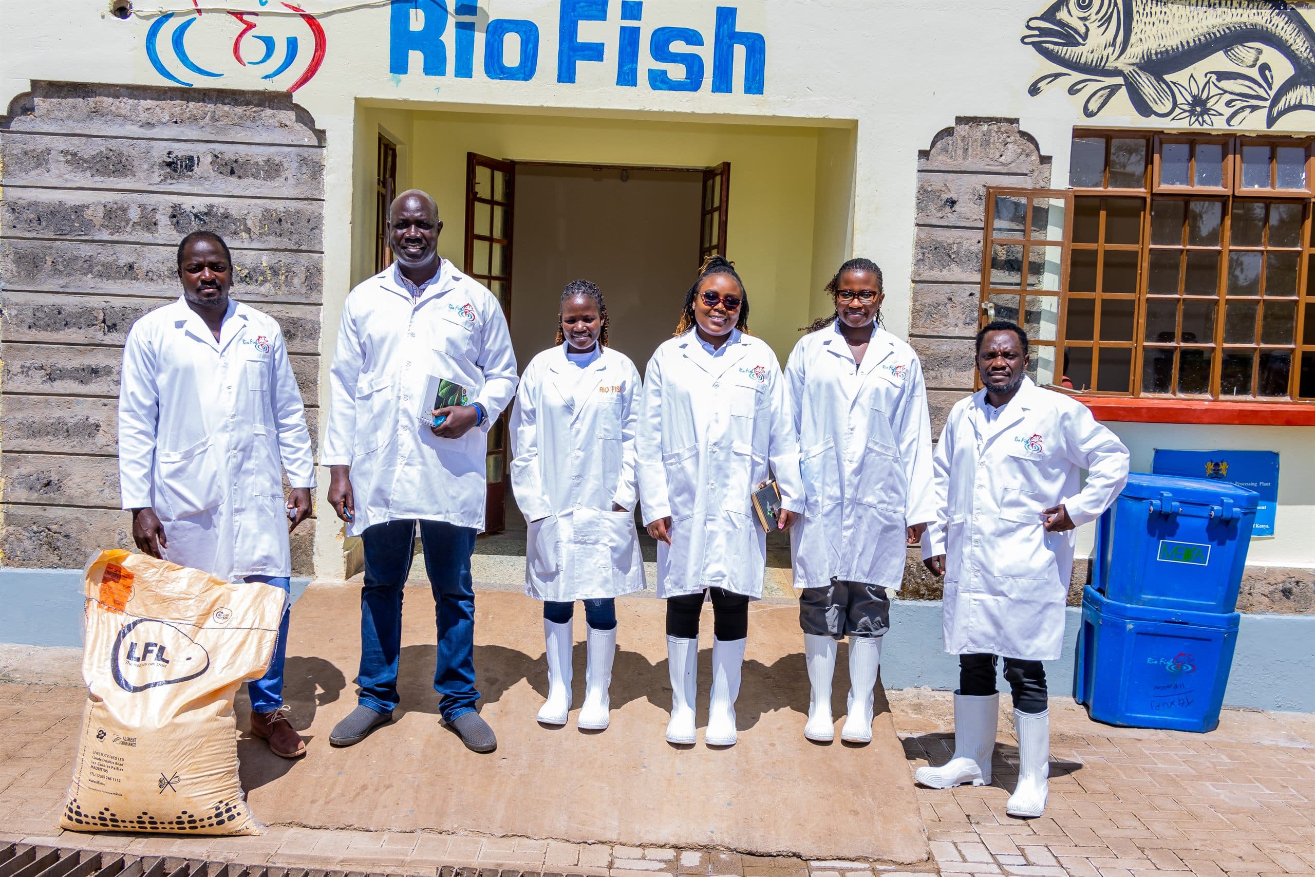 A team in white lab coats outside a fish processing facility